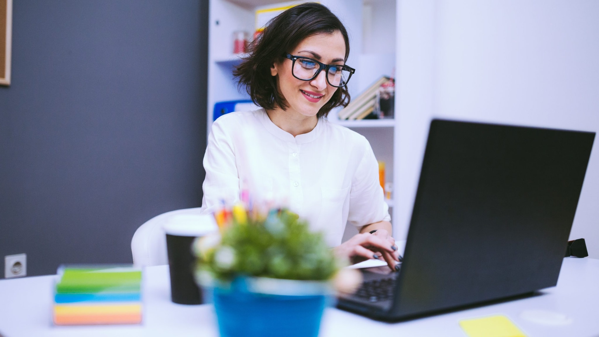 Woman sitting at desk using laptop in dental office.