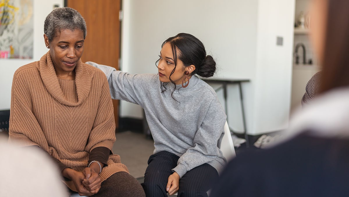 Woman showing support for another woman in a therapy session.