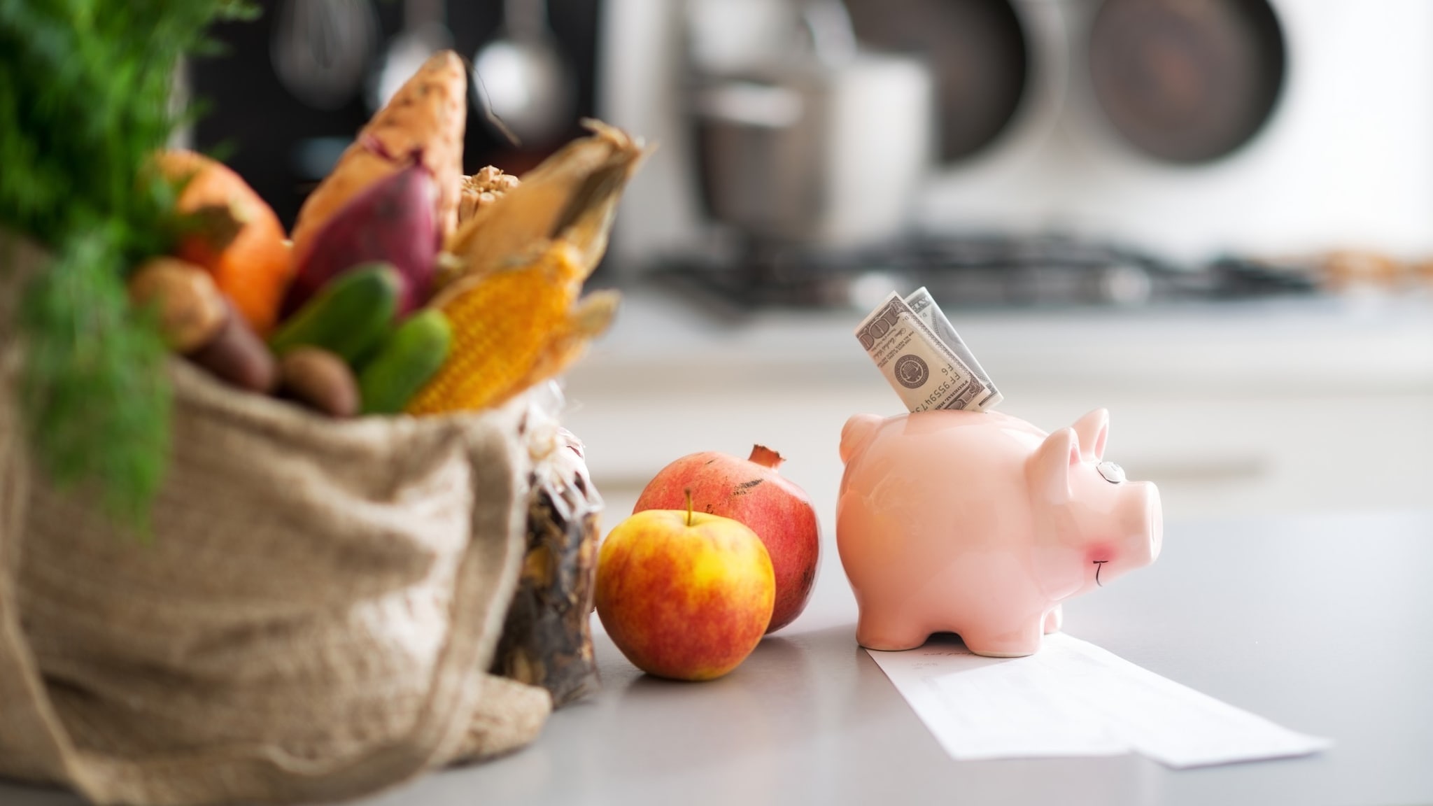 Money in piggy bank and food purchases on table.