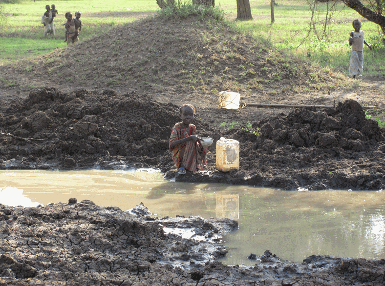 girl drinks from muddy pond