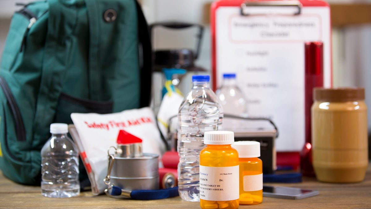 Emergency preparedness items, including a backpack, first aid kit, medications, and bottled water.