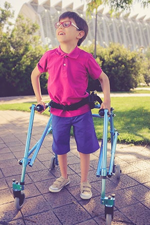 A boy using a walker outside.