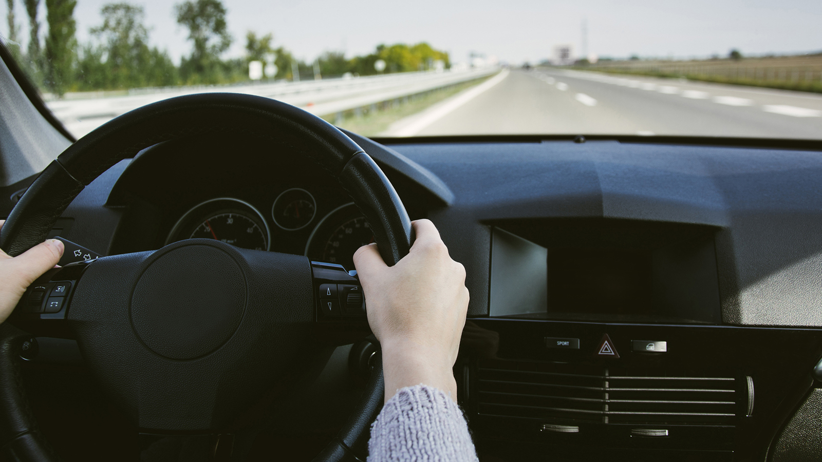 A person driving with both hands on the steering wheel