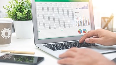 View of a person's laptop screen that contains data tables and charts