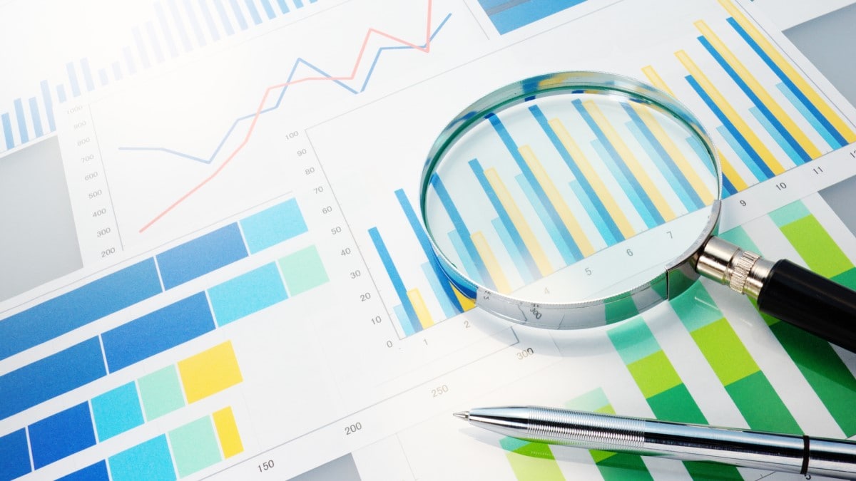 Magnifying glass and pen on top of data charts