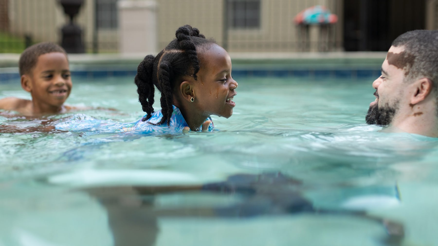 Two Black kids in pool with dad.