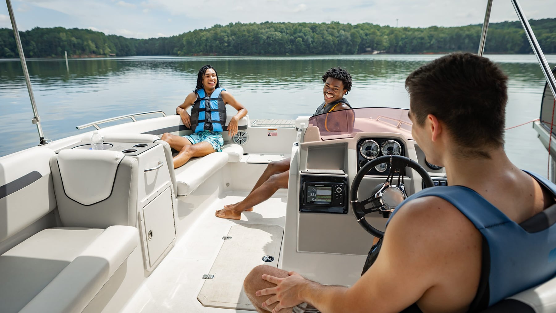 young males with life jackets on boat on lake