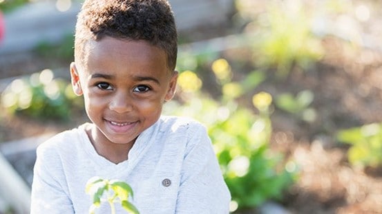 Smile child holding a plant.