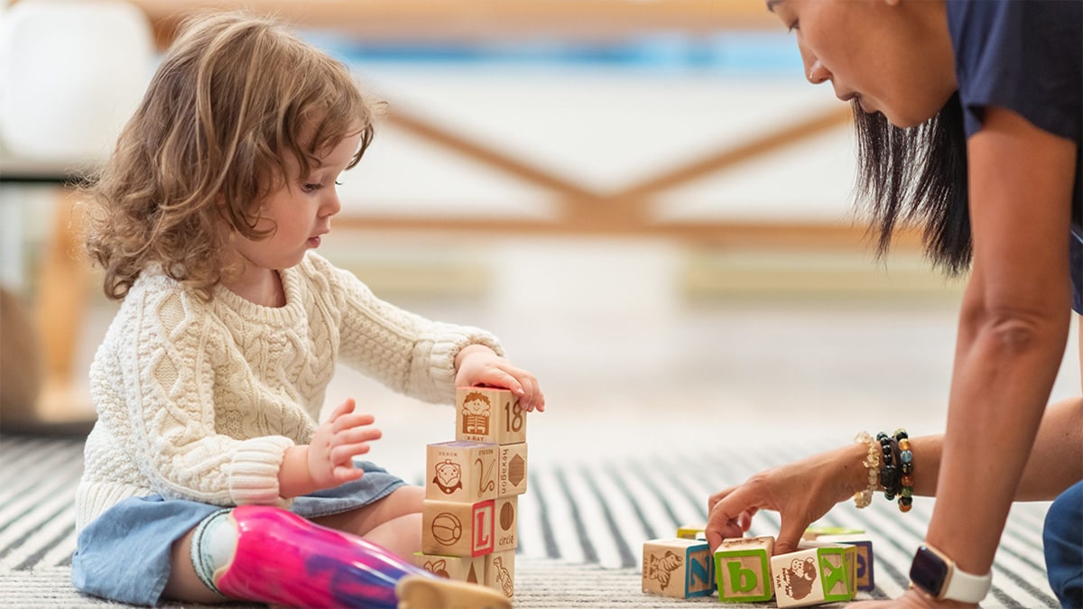 School teacher and young student playing with blocks