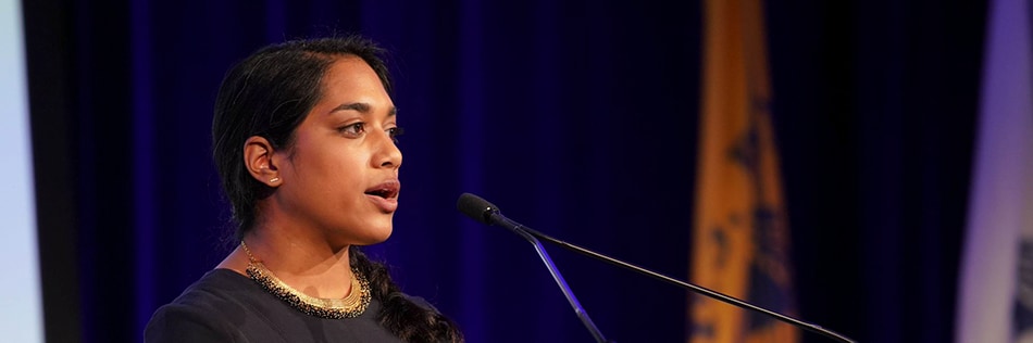 Lady standing on stage in front of microphone.