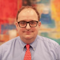 White male with glasses and shirt and tie smiling