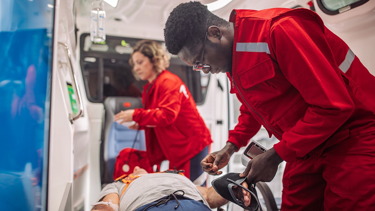 Two EMS technicians working on a patient laying on a gurney in an ambulance