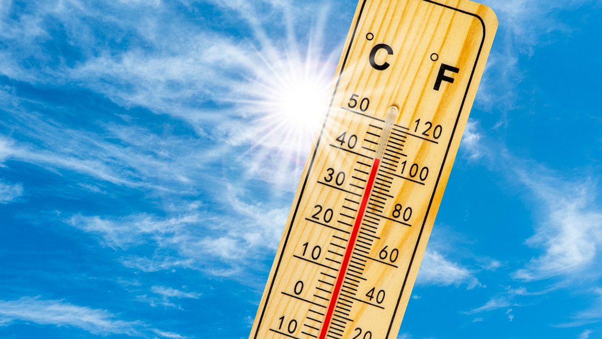 Thermometer sharing heat event temperature data on sunny day with blue skies.