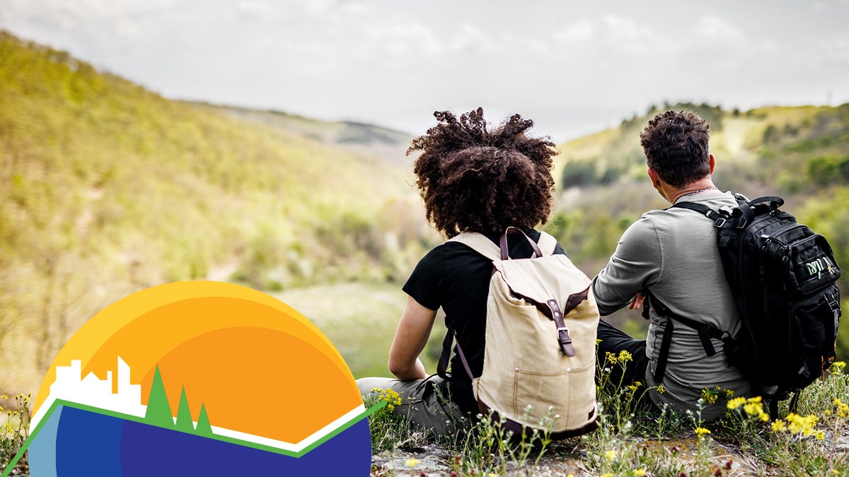 Two seated backpackers overlooking mountainous horizon opposite CDC Tracking Program logo