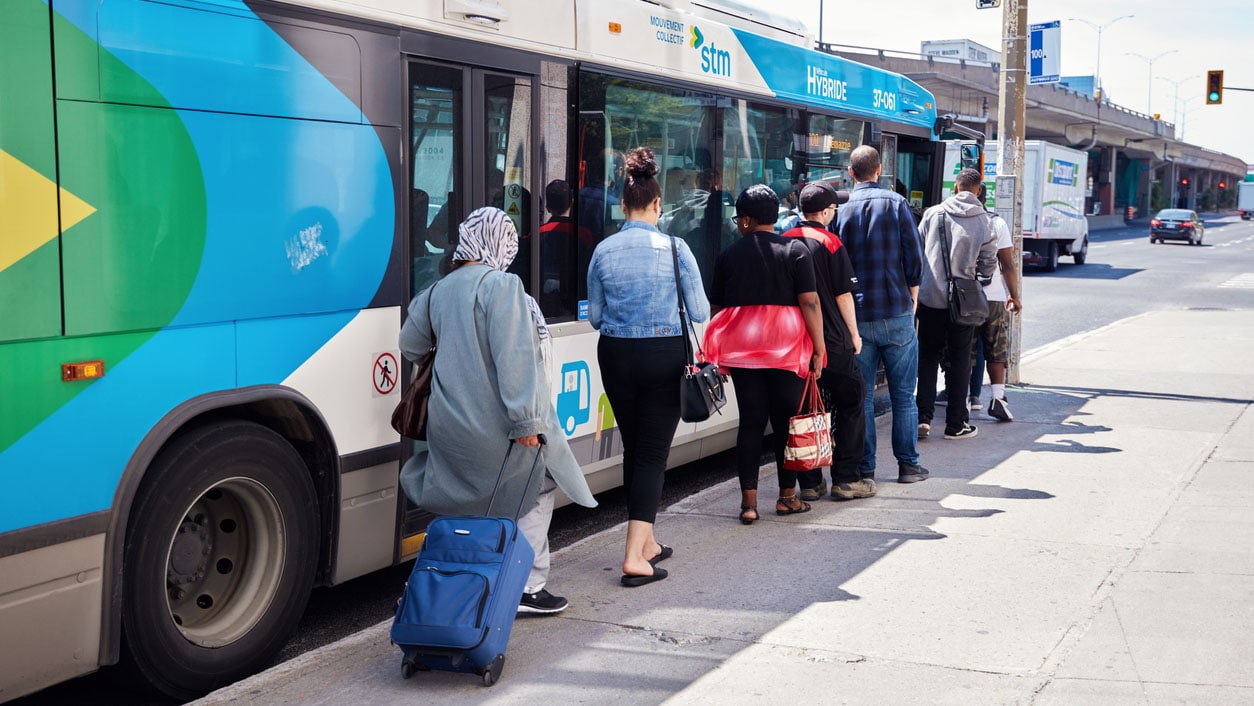 Adults waiting in line to get on the public bus.