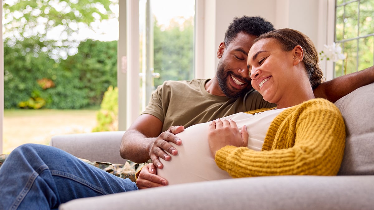 A pregnant couple sitting on a couch