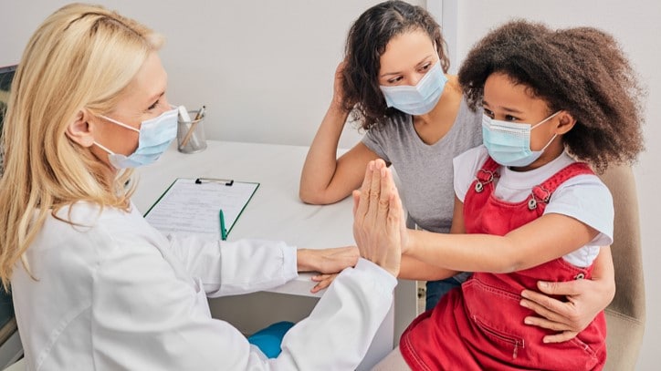 Child and her mother speak with a health care professional.