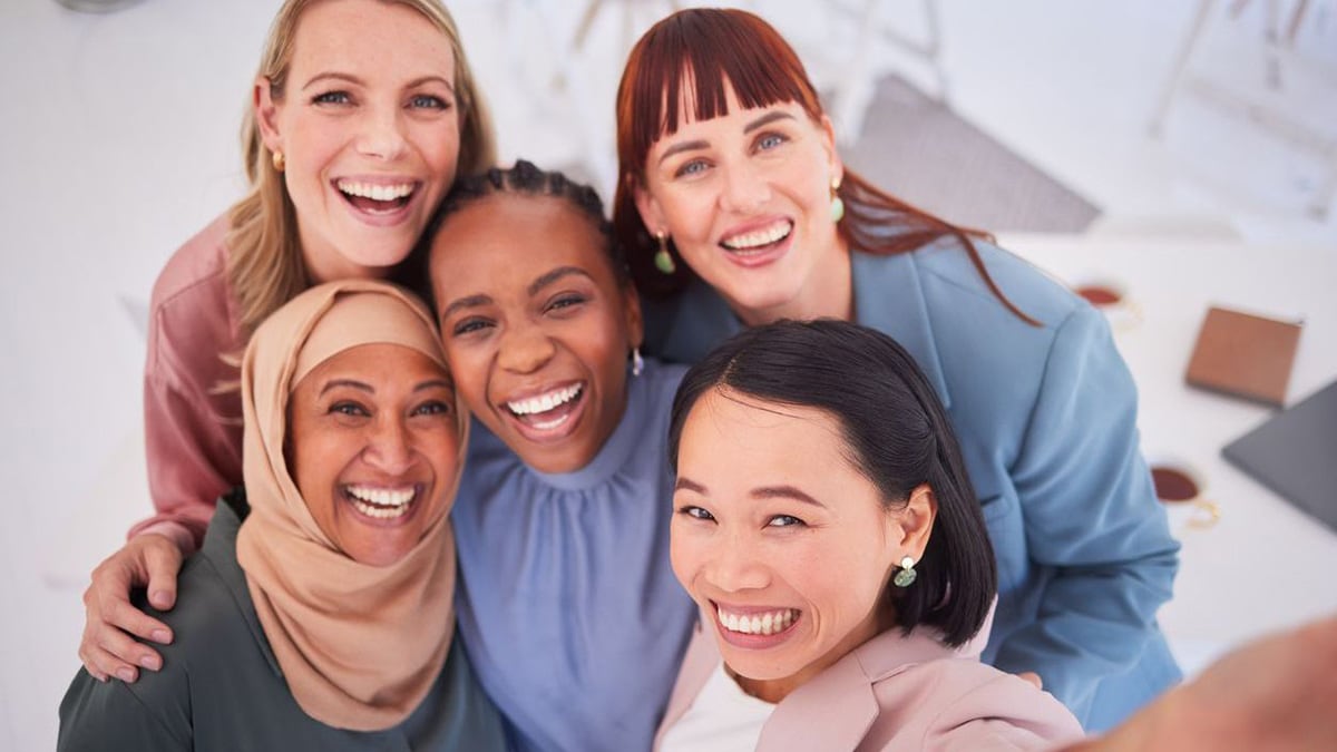 Cinco mujeres paradas muy cerca y sonriendo.