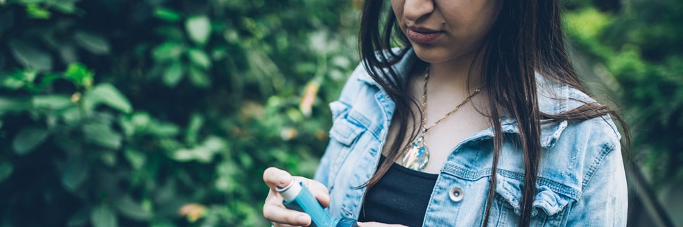 woman holding an inhaler out in the woods