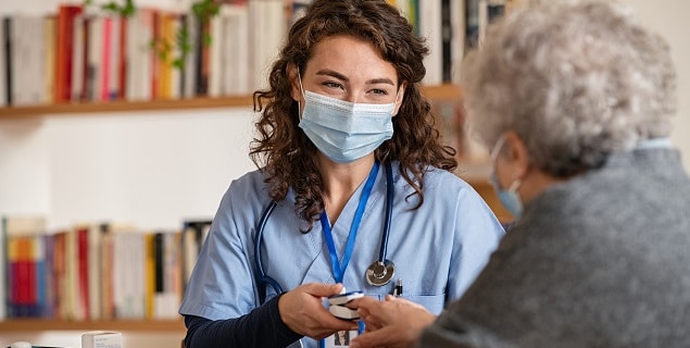 Female doctor and elder woman wearing masks during consultation.  