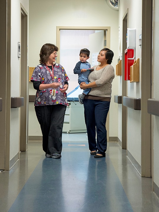 Nurse talking to an American Indian female patient holding her son in her harms.