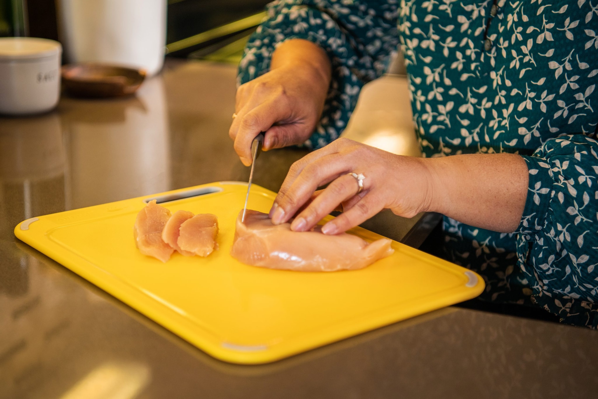 Woman cutting raw chicken on cutting board