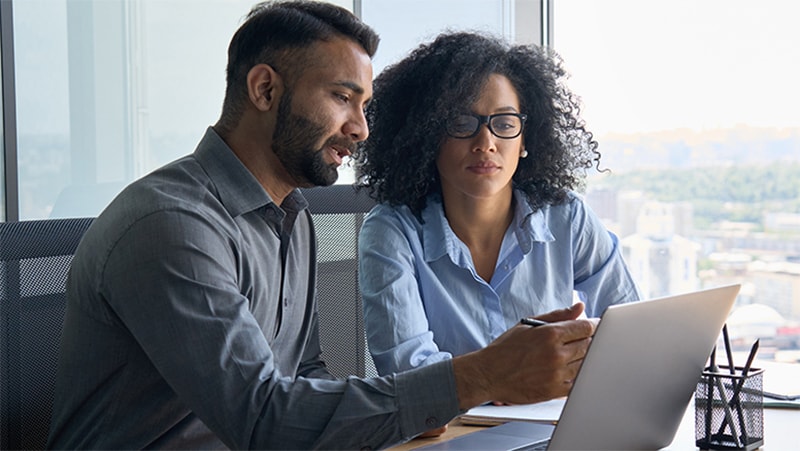 Photo of woman and a man pointing at a laptop.