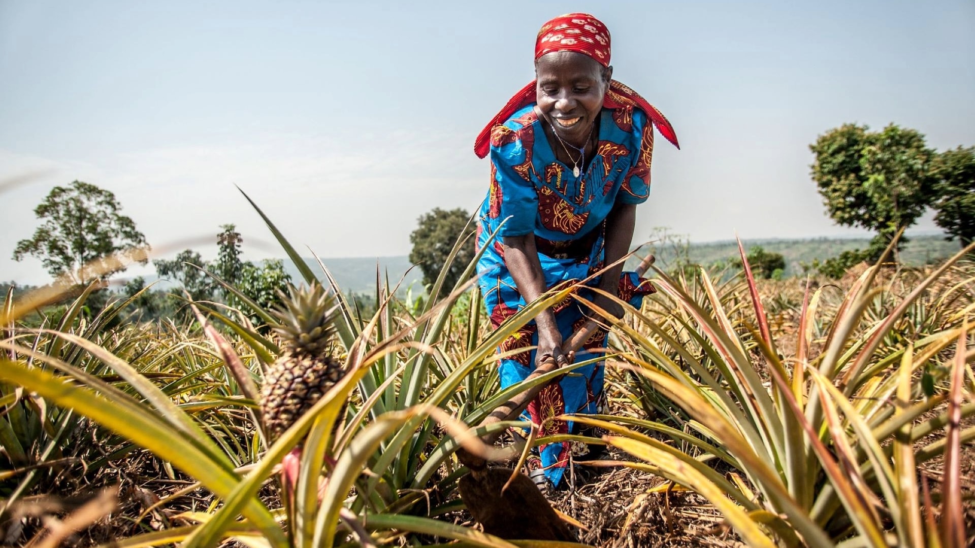 African lady dressed in traditional clothing in a field.