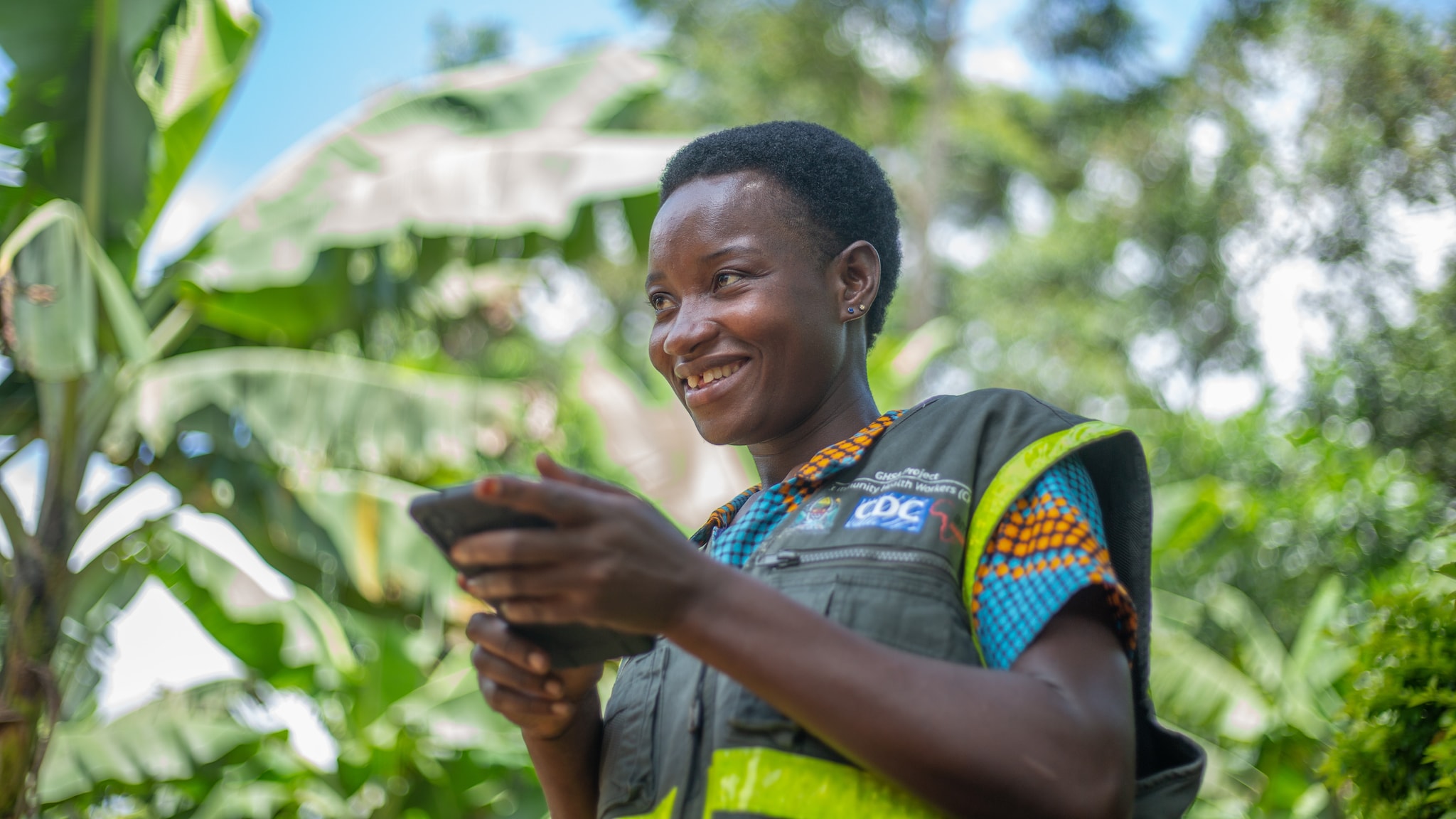 Healthcare worker smiling with a tablet wearing a CDC vest.