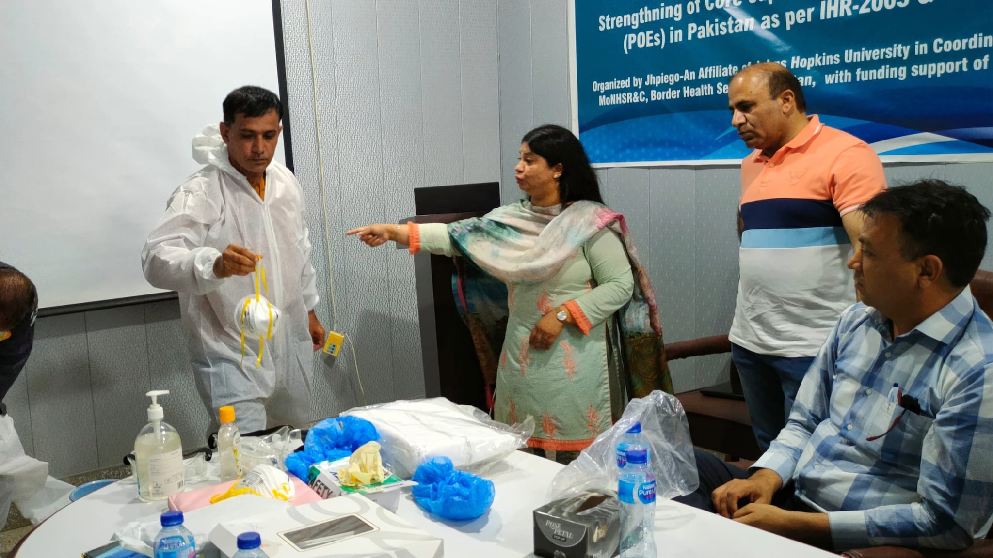 Dr. Nadia Noreen working with team to demonstrate correct procedures for personal protective equipment