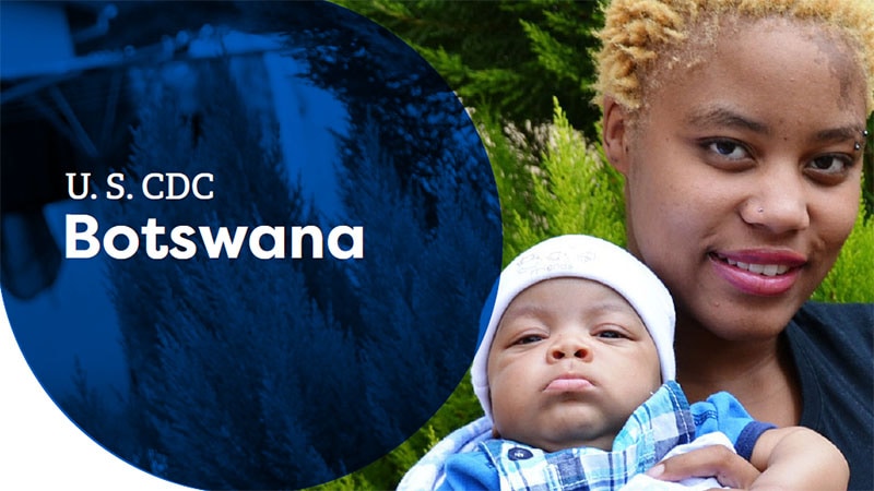 A woman in Botswana holding a baby, both smiling gently in a natural outdoor setting.