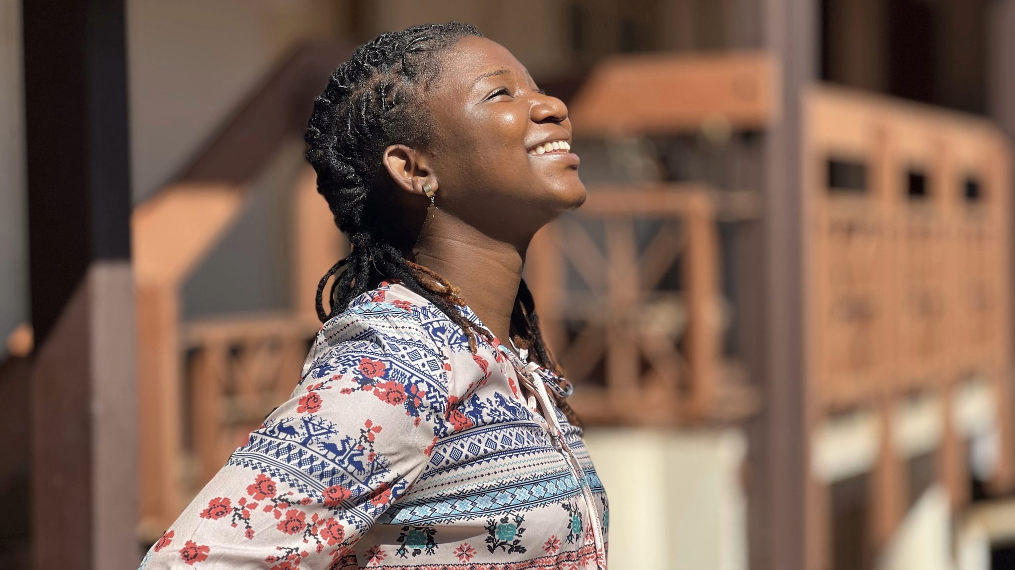 Photo of a young woman smiling and standing outdoors in the sun