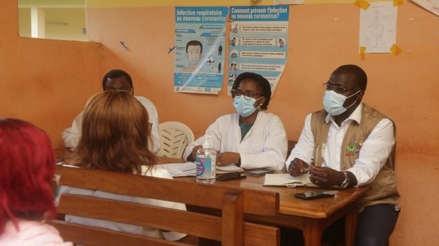 Three masked individuals sit in the front of room during an FETP training.