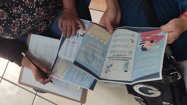 This image shows two individuals holding and flipping through educational COVID-19 pamphlets.