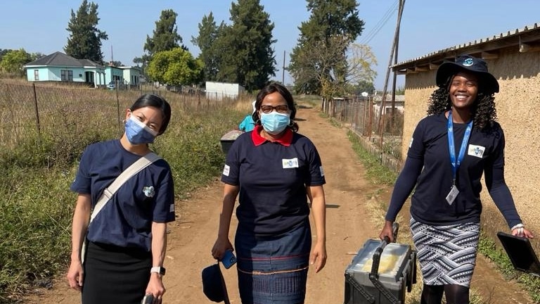 Three CDC professionals stand outdoors on a dirt road.