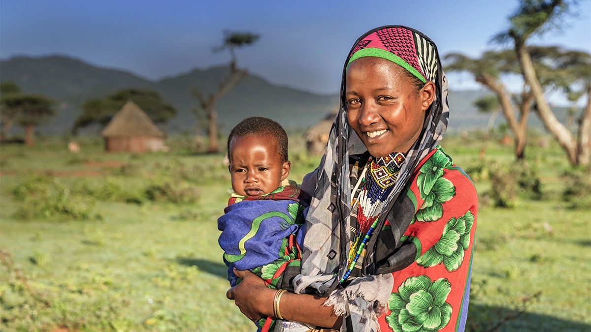 CDC’s Global Health Centers important work around the world. Woman holding child in open field.