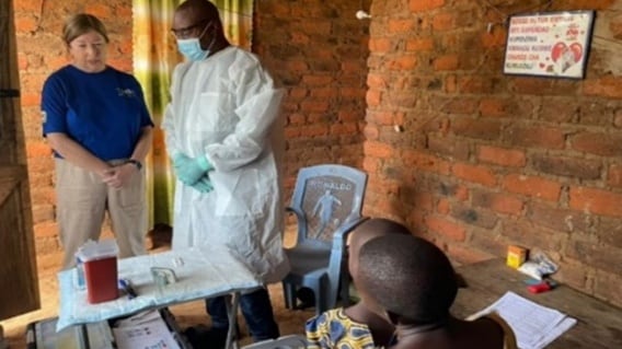 CDC Alison Johnson wearing a blue shit and beige pants and a man in a lab coat monitor field staff conducting an interview in a household in Tanzania.