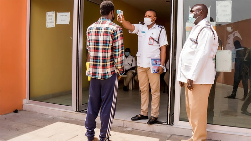 A Nigerian Port Health officer conducts a temperature check for a passenger crossing a land border