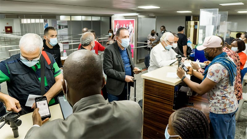 Port Health officers utilizing QR code scanner to review vaccination cards of travelers at airport desk