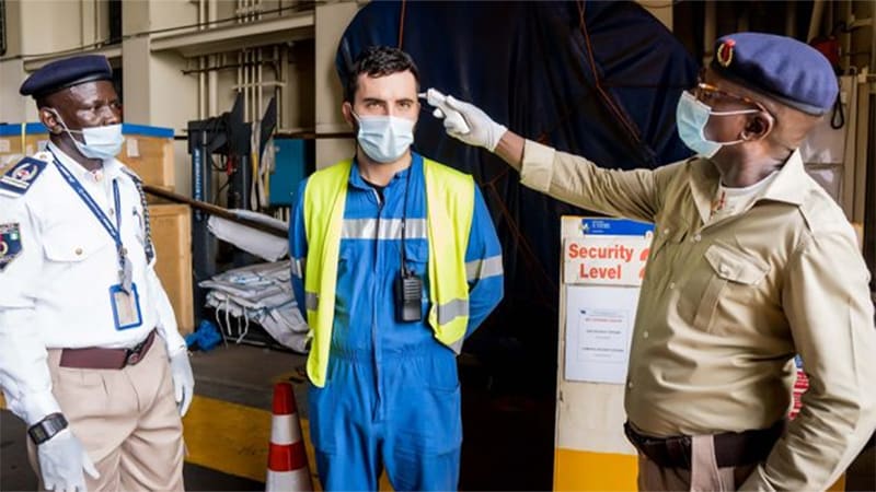 Two Port Health officers. One is taking the temperature of a crew member docked at Nigerian Port.