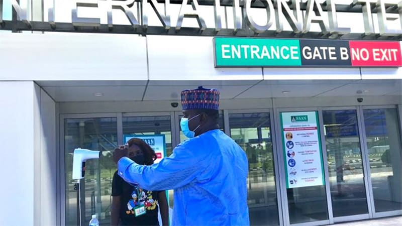 Man and woman wearing masks standing in front of airport