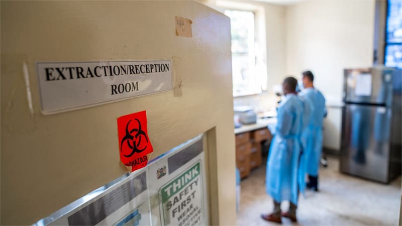 two people in the lab. Sign on door reads Extraction/Reception Room