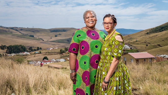 Two women stand side-by-side in a field.