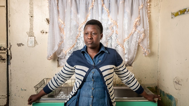 Nthabiseng, a community worker in her mid-20s, leaning against a desk