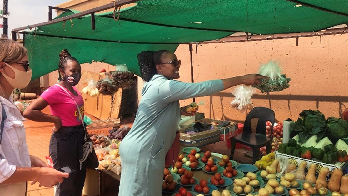 Public health workers in front of program participant's vegetable stand.