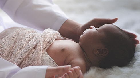 Madre acariciando a un bebé mientras duerme