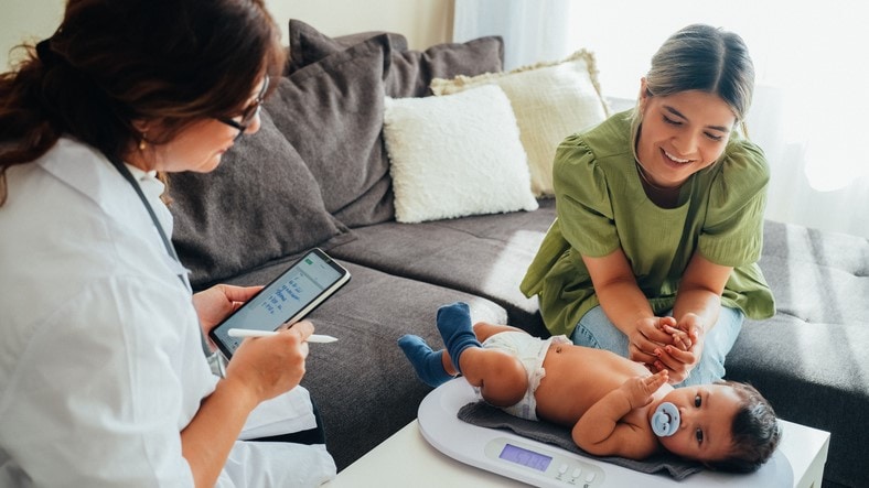 Health care provider and a mother looking at a baby on an infant scale.