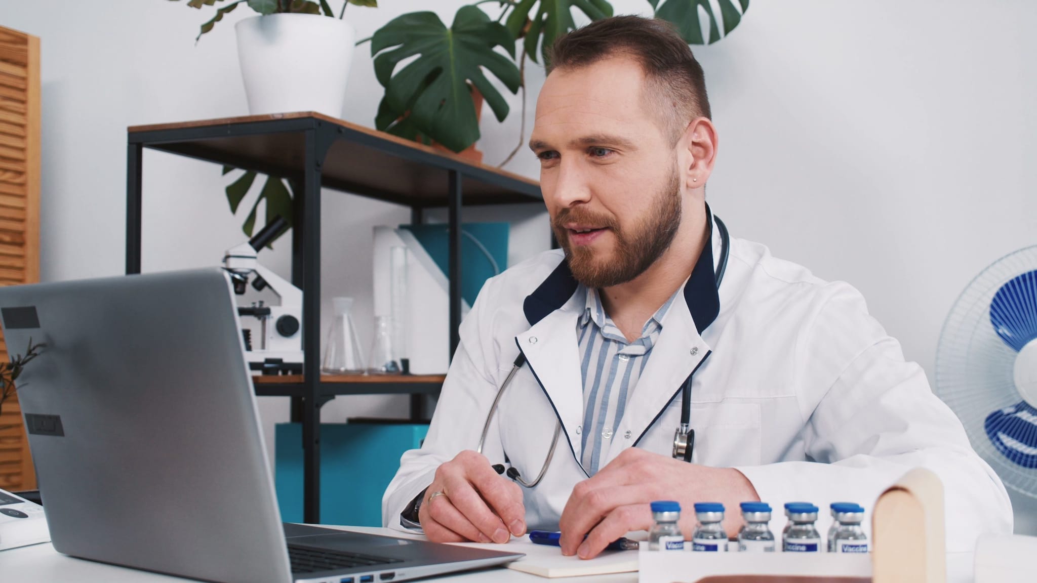 Health care professional sitting at a desk with a laptop computer.