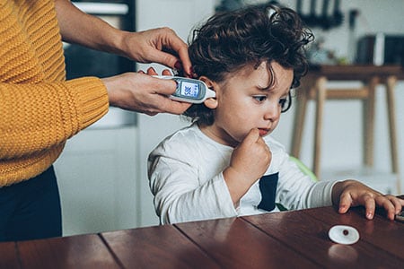 Una madre le toma la temperatura a su hija con un termómetro digital.