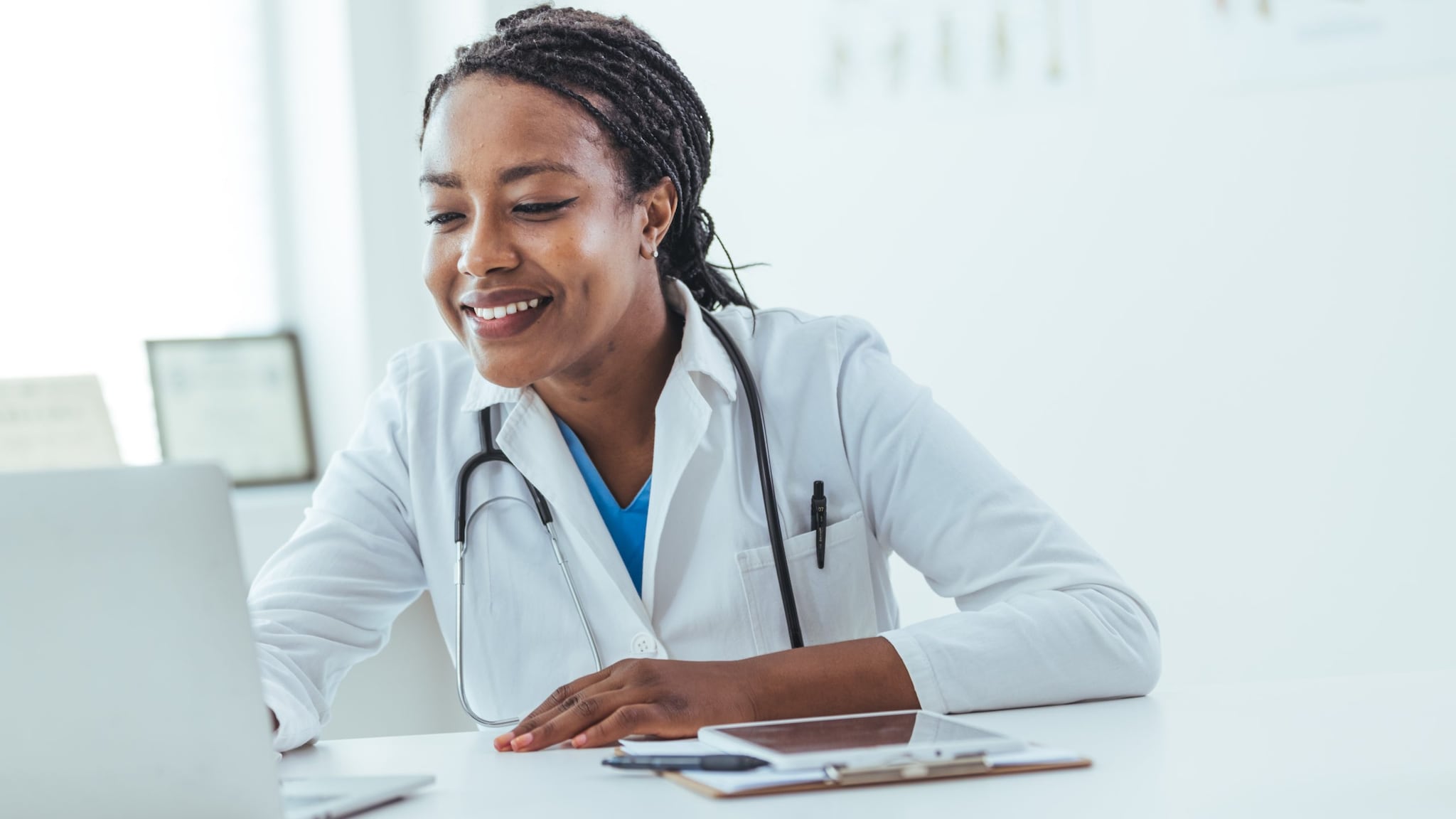 A smiling healthcare provider studies at a laptop.